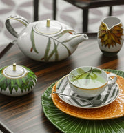 Vista Alegre | Amazonia Tea Cup And Saucer featuring green leaf pattern on black-and-white striped saucer, part of a botanical-themed tabletop tea set.
