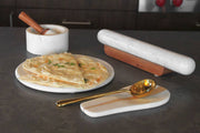 Verve Culture - White Marble Rolling Pin and Wood Base displayed on a kitchen countertop with flatbread, marble mortar, and gold-tone spoon, showcasing elegant kitchen aesthetics.