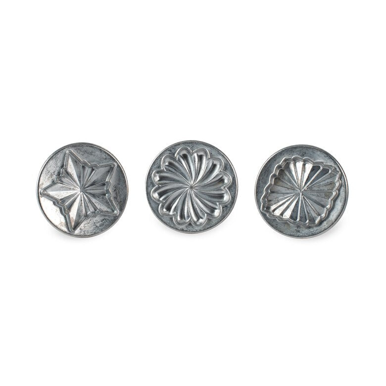 Nordic Ware | Pretty Pleated Cookie Stamps featuring circular metal stamps with floral, star, and diamond designs for creating detailed 3D cookie imprints.
