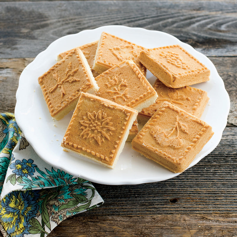 Nordic Ware | English Shortbread Pan featuring intricate flower and fruit designs, presented with freshly baked cookies on a wooden table.