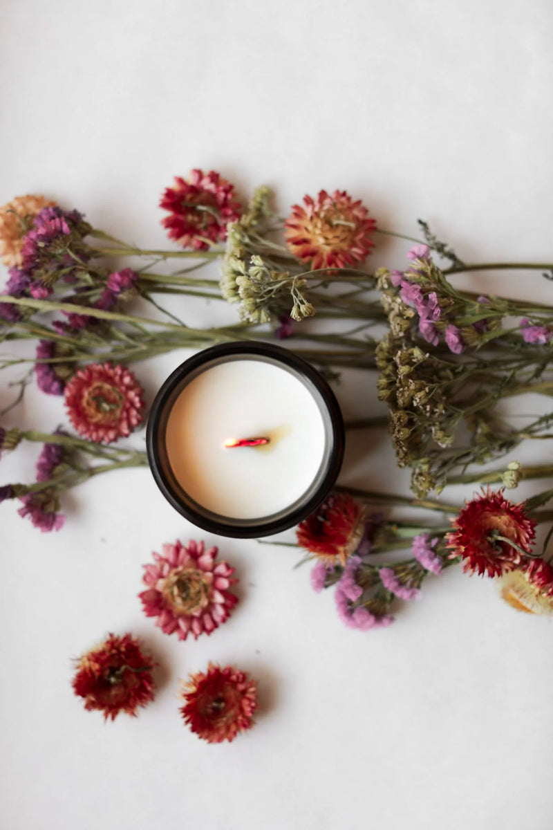 Among the Flowers | Essential Oil + Soy Wax Candle Domes in a dark vessel, surrounded by dried flowers, showcasing a natural, low-smoke candle option.