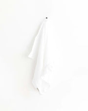 MagicLinen - Ruffle trim tea towel hangs on a hook, showcasing its elegant design and practicality for kitchen use.