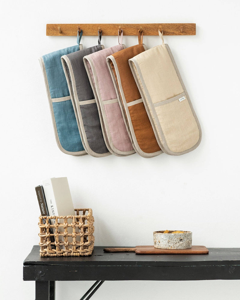 Forest green gingham double oven mitts hanging on a wall, designed to protect hands from heat, crafted from excess linen for sustainability.