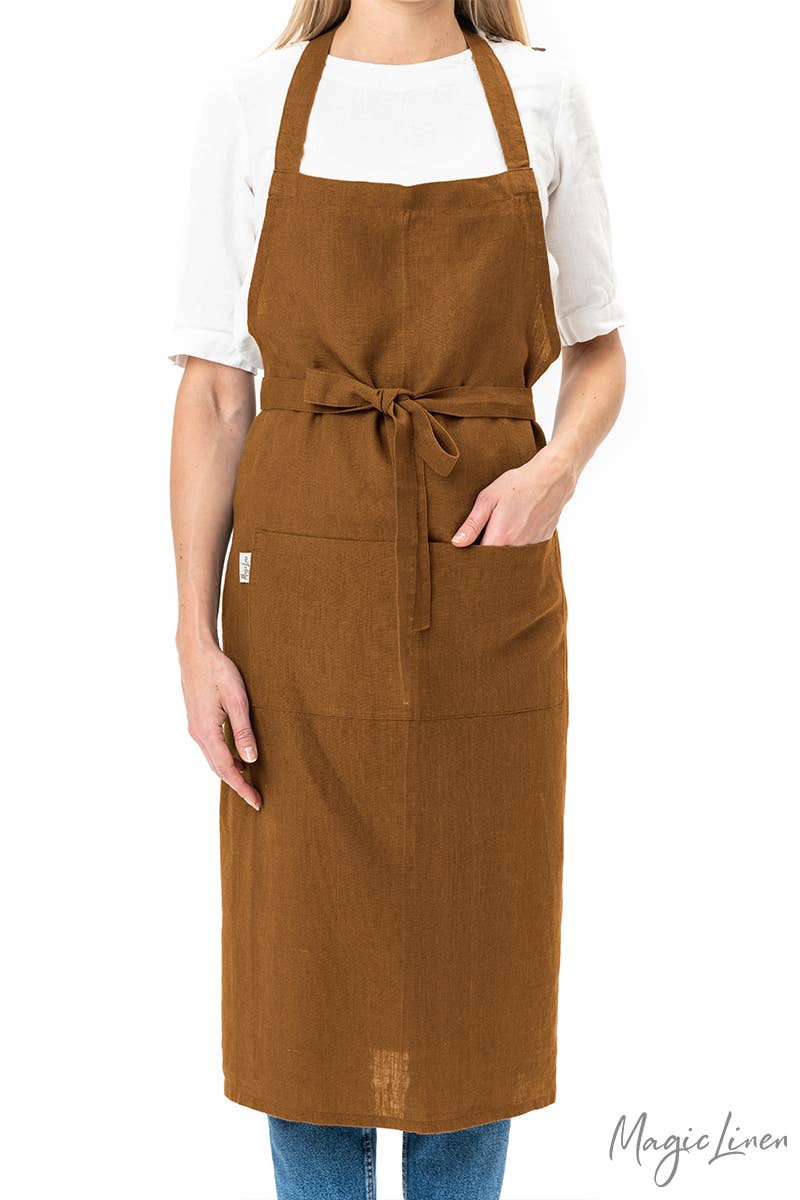 Person wearing MagicLinen's Charcoal Grey Linen Bib Apron with Pockets, showcasing its stylish and functional design ideal for cooking or gardening.