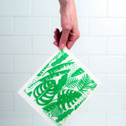 Bespoke Provisions - Tropical Leaves Swedish Dishcloth held in hand, showcasing green leaf design. Made from biodegradable materials, ideal for cleaning various surfaces.