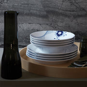 Royal Copenhagen | Blue Mega Deep Plate, 24cm, featuring a blue floral motif, sits atop a wooden tray alongside glassware and cutlery, embodying elegant Danish design.