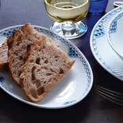 Royal Copenhagen's Princess Plate, 27cm, elegantly displays crusty sourdough slices, showcasing its refined lace border and classic design, complemented by a stemmed glass of white wine.