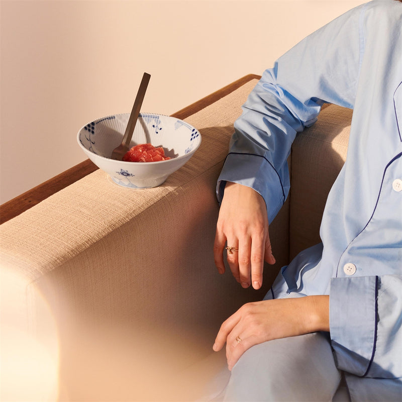 Royal Copenhagen | Blue Elements Bowl 78cl, resting on a sofa, holds segmented red fruit. Features hand-painted floral designs and iconic edges, ideal for snacks.