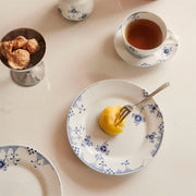 Royal Copenhagen | Blue Elements Plate, 19cm, elegantly holds a dome-shaped yellow dessert, with a matching teacup and cookies on a pale countertop.