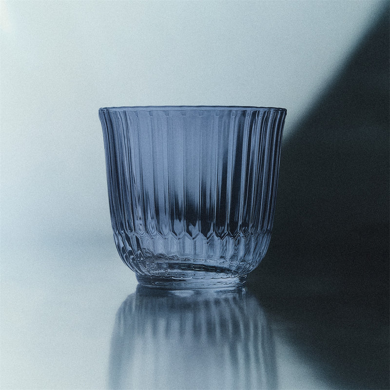 Royal Copenhagen | Waves Water Glass, Blue, Set of 2, featuring ribbed, fluted sides on a reflective surface, embodying both style and practicality for diverse table settings.