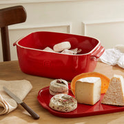 Emile Henry | Cheese Box, Burgundy, showcased with cheeses and knife, illustrating its versatility as a storage and serving piece for kitchen enthusiasts.