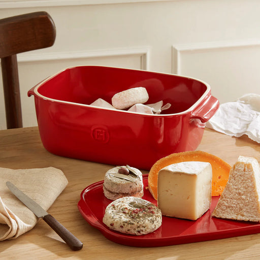 Emile Henry | Cheese Box, Burgundy, showcased with cheeses and knife, illustrating its versatility as a storage and serving piece for kitchen enthusiasts.