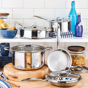 Heritage Steel | 10 Piece Cookware Set displayed on a kitchen countertop with coordinating accessories, including a wooden cutting board, glass jars, and decorative bottles.