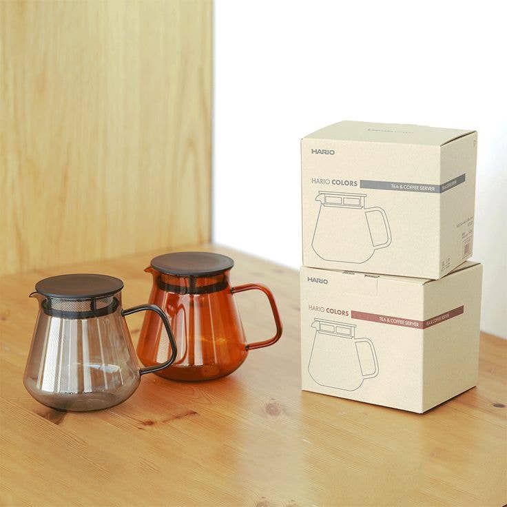 HARIO USA - HARIO Colors Glass Coffee and Tea Server, 600ml: Grey, with lid and mesh filter, next to packaging on a wooden surface.