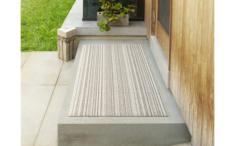 Chilewich | Skinny Striped Shag Mat - Ocean, tufted and durable floor mat on concrete step, ideal for indoor or outdoor use with non-skid backing.