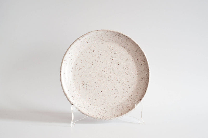 RachaelPots - Salad Plate: Sage; off-white ceramic with a brown speckled pattern, slightly upturned lip, displayed on a stand. Hand-thrown in Brooklyn, NY.