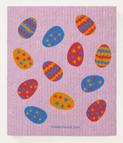 Three Bluebirds Swedish Dishcloth featuring colorful Easter egg designs on a pink mat, ideal for sustainable kitchen use, absorbs 20x its weight.