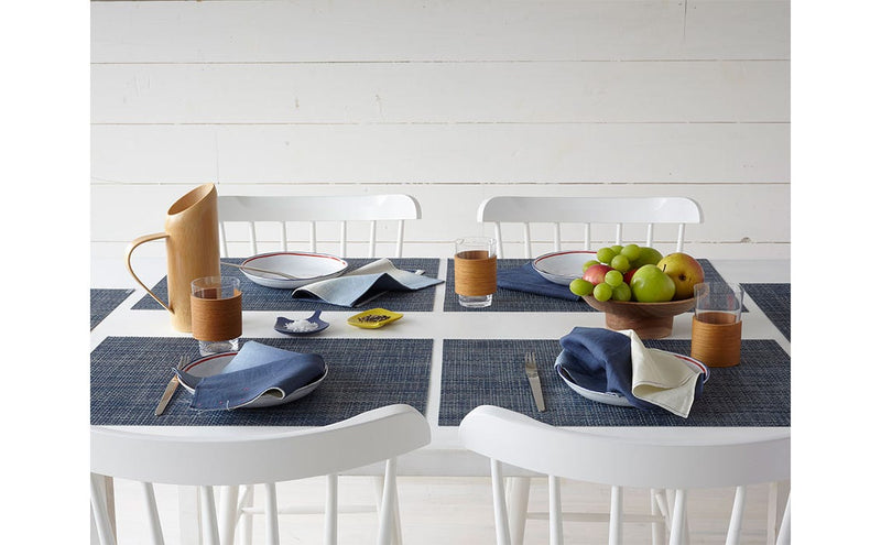 Chilewich Basketweave Rectangle Placemats in Denim on a dining table with tableware and fruit, showcasing refined design and understated elegance.