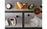Chilewich Ombré Rectangle Placemat on a table with food, including bread, cheese, and fruit, highlighting its textured weave and subtle color gradient.