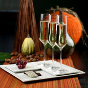 Zwiesel Fortessa | Pure Champagne Flute, Single: Three elegant flutes filled with sparkling wine, set on an autumn-themed table with gourmet chocolates and grapes.