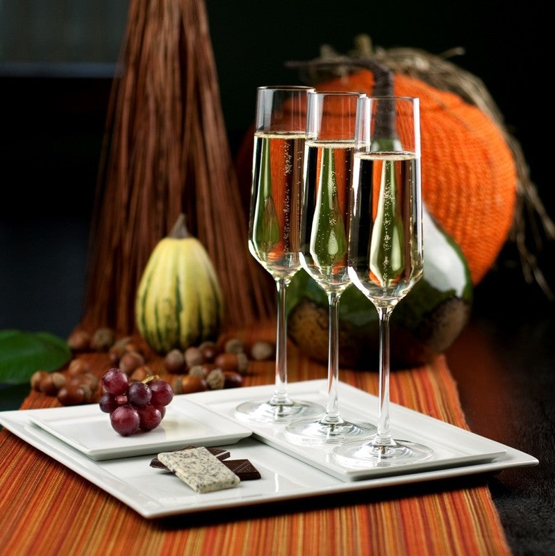 Zwiesel Fortessa | Pure Champagne Flute, Single: Three elegant flutes filled with sparkling wine, set on an autumn-themed table with gourmet chocolates and grapes.