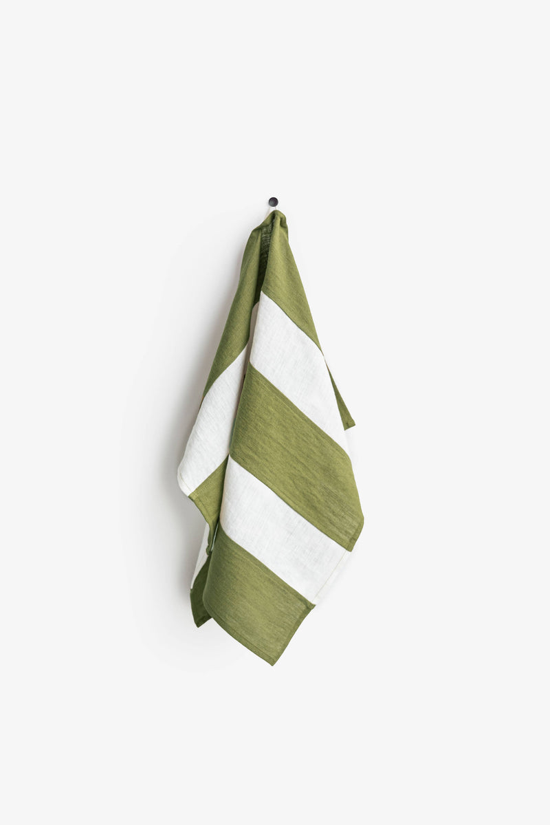 Striped linen tea towel with hanging loop displayed on a hook, part of MagicLinen's zero-waste collection, emphasizing sustainability and practicality for kitchen use.