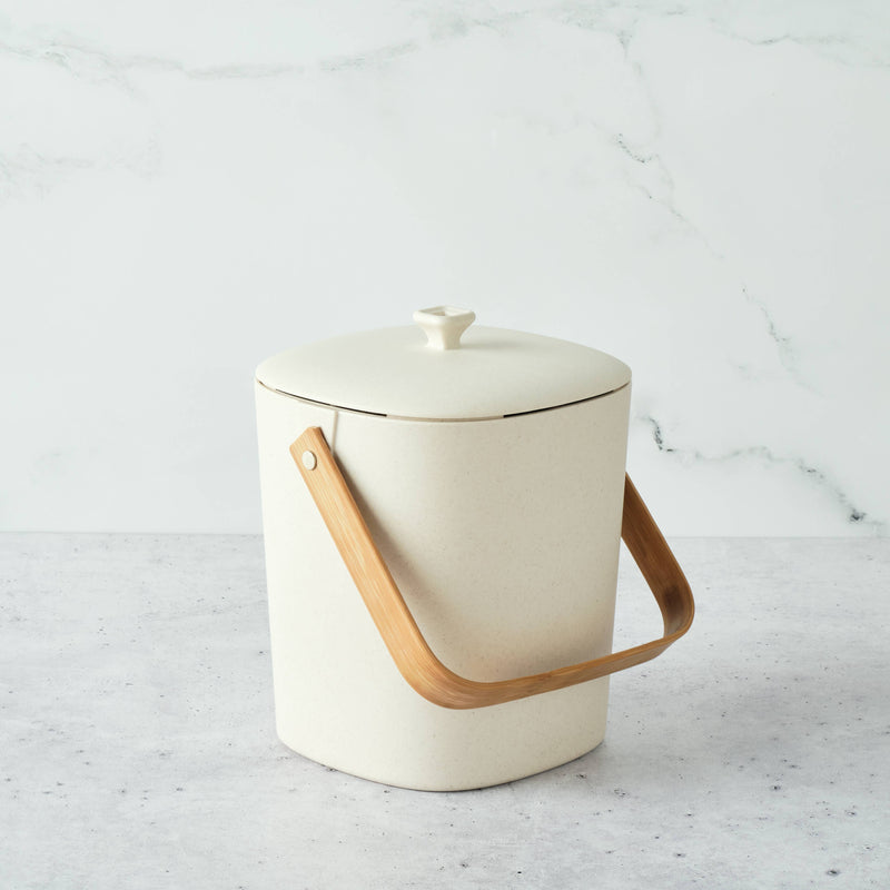 Bamboozle - Astrik Composter: Natural, a small off-white bin with a bamboo handle, designed for sustainable kitchen scrap collection. Durable, odor-blocking, perfect for eco-conscious chefs.