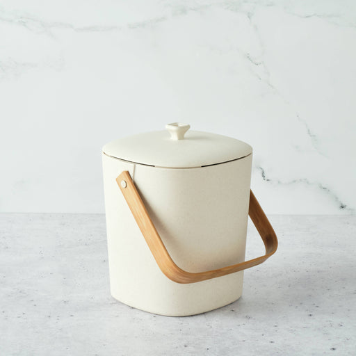 Bamboozle - Astrik Composter: Natural, a small off-white bin with a bamboo handle, designed for sustainable kitchen scrap collection. Durable, odor-blocking, perfect for eco-conscious chefs.
