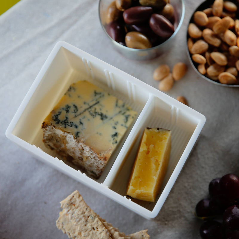 CapaBunga® Cheese Vault with blue and yellow cheese, surrounded by olives, peanuts, crackers, and grapes; ideal for artisan cheese storage.