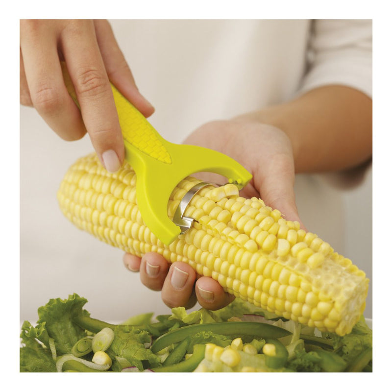 Person using Kuhn Rikon Corn Zipper, Yellow, to strip kernels from a cooked corn cob into a salad, showcasing its efficient and safe design.