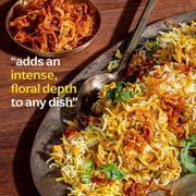 Diaspora Spices Co. - Kashmiri Saffron (Grade A Threads) enhances chicken biryani with intense, floral aroma; features spiced chicken, fried onions, and cilantro garnish.