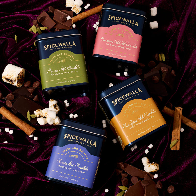 Spicewalla | Chai Spiced Hot Chocolate tin nestled among chocolate, marshmallows, and spices, offering a uniquely spiced cocoa experience with ginger, cinnamon, and cardamom.