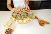 Bee's Wrap - New! Garden Party - Assorted 3 Pack held over a bowl, highlighting reusable fabric food wraps for sustainable food storage.