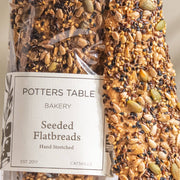 Potters Table - Seeded Olive Oil Flatbreads in bakery-style packaging, hand-stretched and topped with a mix of seeds, showcasing craftsmanship and quality.