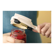 A person uses the Kuhn Rikon | The Gripper Jar Opener to effortlessly twist open a tomato sauce jar lid, showcasing its effective grip and easy handling.