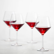 Zwiesel Fortessa | Pure Burgundy Goblet, Single: Four elegant, partially filled Tritan Crystal goblets with angled bowls and stems, showcasing postmodern design and sophistication in wine glassware.