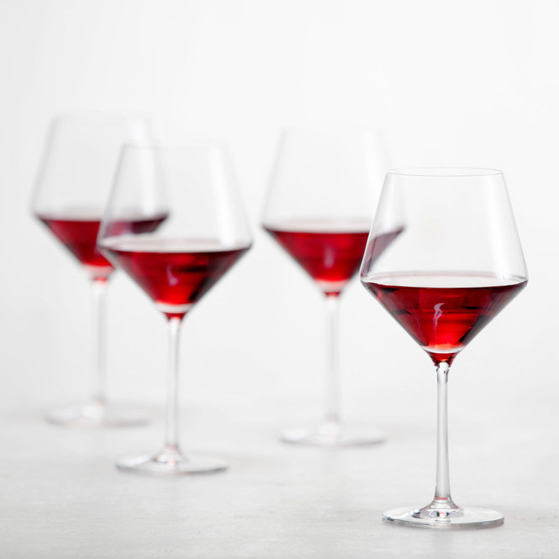Zwiesel Fortessa | Pure Burgundy Goblet, Single: Four elegant, partially filled Tritan Crystal goblets with angled bowls and stems, showcasing postmodern design and sophistication in wine glassware.