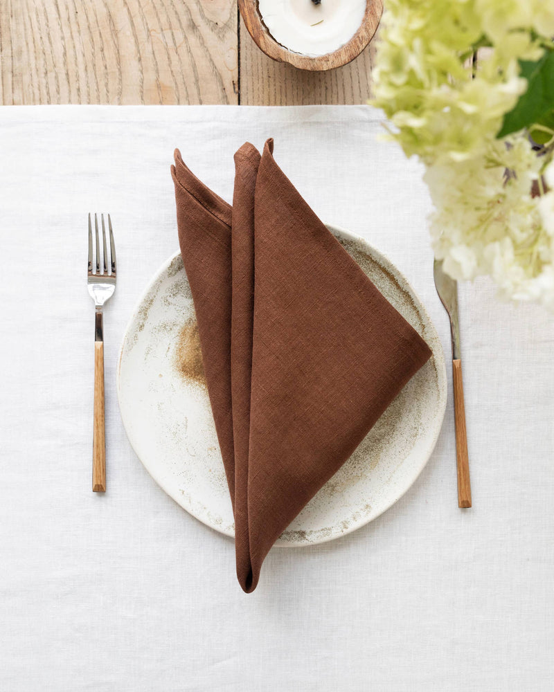 Set of 2 linen napkins on a white plate with a fork, showcasing premium, versatile table decor suitable for everyday use or special occasions.