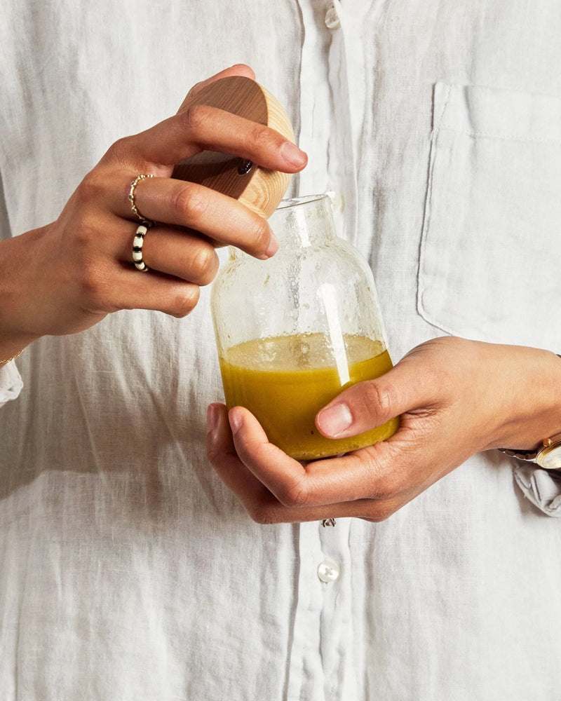 Holcomb Studio Totter Salad Dressing Shaker held by a person, highlighting its ergonomic design for easy mixing and pouring of dressings.