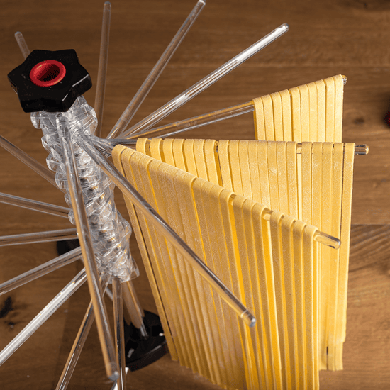 Marcato | Tacapasta Pasta Drying Rack with freshly cut pasta strips draped over its arms, designed to dry up to 2 lbs of pasta evenly.