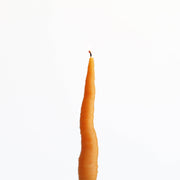 Carrot-shaped beeswax candle with a lit wick, molded from a real carrot, designed for home decor.