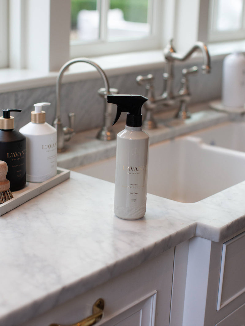 L'AVANT Collective - Fresh Linen Multipurpose Cleaner in a recycled spray bottle on a kitchen counter, perfect for grease removal and surface cleaning.