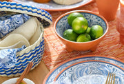 Verve Culture - Mexican Woven Palm Tortilla Basket showcased on a tabletop with a footed bowl of limes, a plate, and a gold-tone fork.