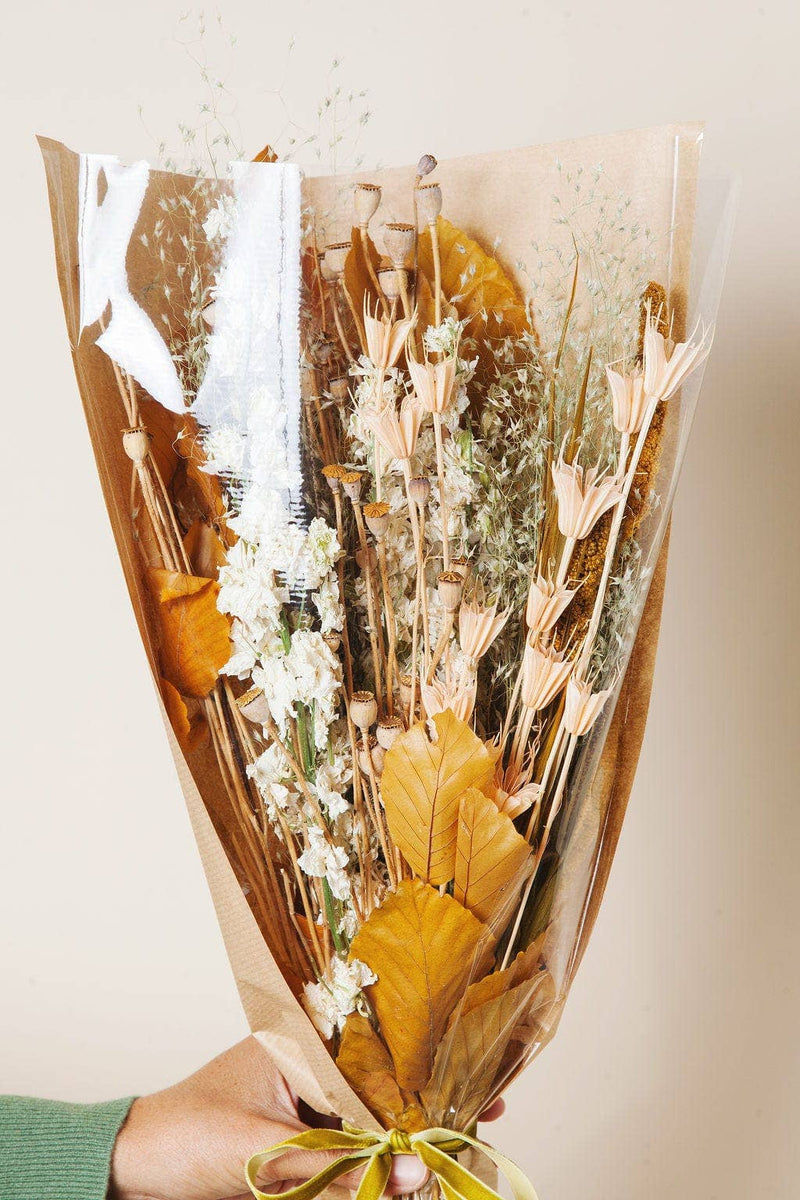 Idlewild Floral Co. - Golden Fall Market Bouquet: A rustic bouquet of dried beige blooms, poppy pods, grasses, and broad leaves, wrapped in kraft paper with green velvet ribbon.