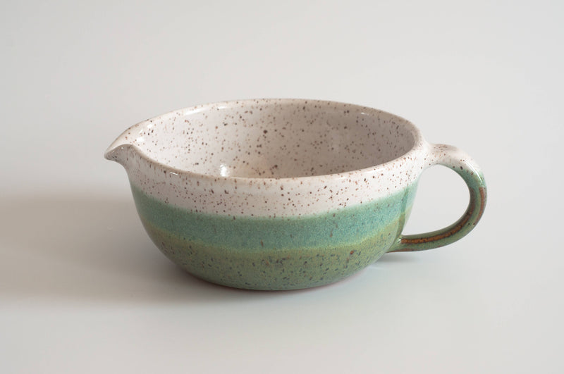 RachaelPots - Salad Dressing Bowl: Coral with a speckled design, featuring a handle, pour spout, and garlic scraper, perfect for dressings or guacamole.