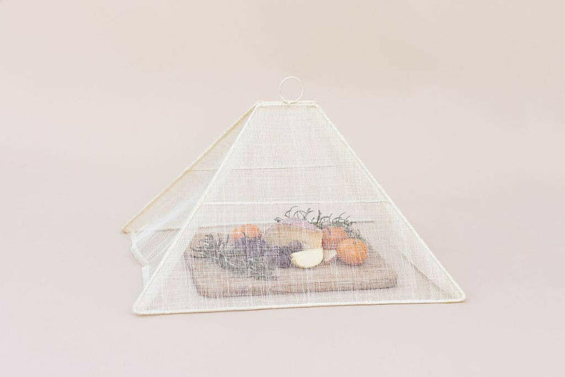NEEPA HUT | Collapsible Woven Food Tent - Rose Pink, elegantly covering fruit on a cutting board, showcasing its unique handmade design for stylish outdoor dining.