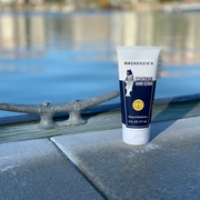 Mackenzie's Fisherman Hand Scrub (6 fl oz) on a dock, ideal for cleaning and deodorizing hands, perfect for cooks, gardeners, and fishermen.