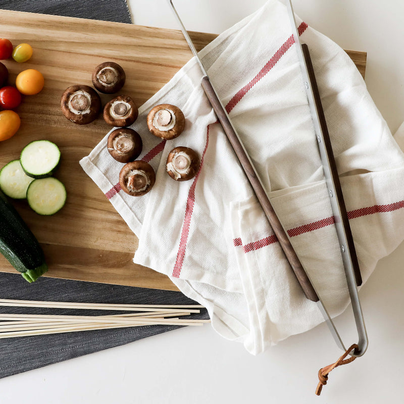 Lamson 20 Heavy Duty Walnut BBQ Tongs on a cutting board with vegetables and mushrooms nearby, highlighting their practicality for kitchen use.