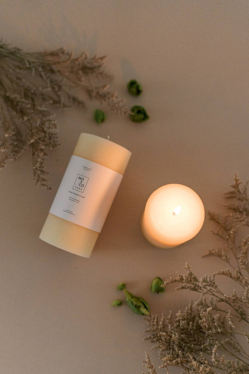 Mo&Co Home - 100% Beeswax Pillar Candles | Natural White: 3x6 Inch, displayed beside a green plant, showcasing its elegant design and eco-friendly features.