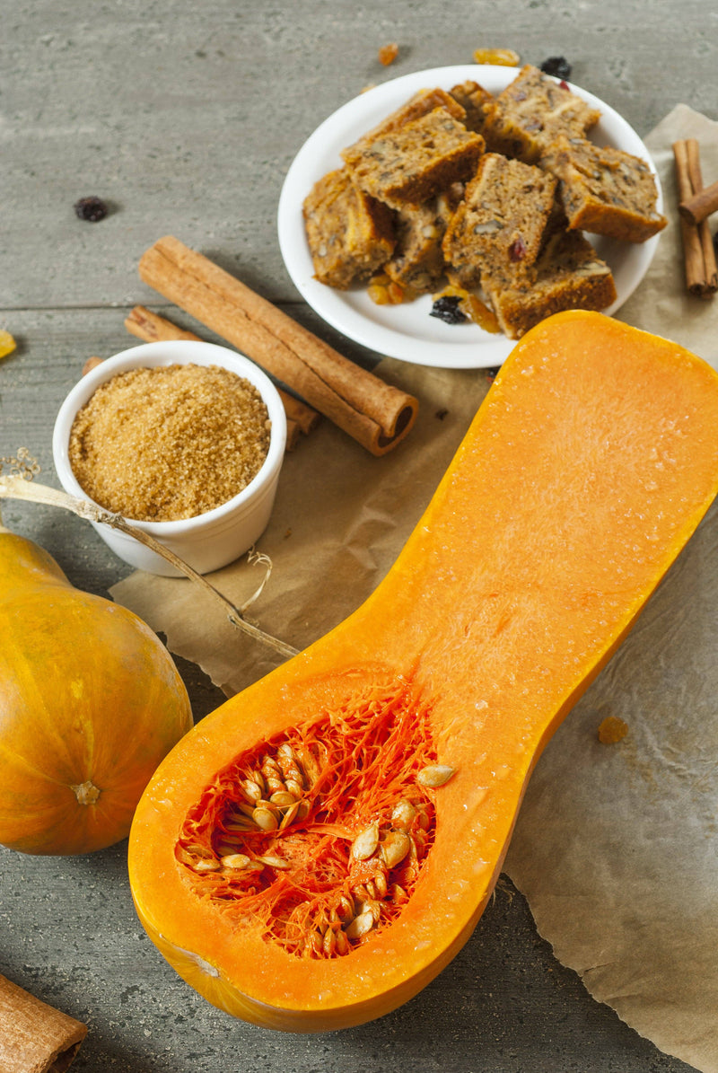 Bentley Seed Co. - Squash-Butternut Waltham 1939 seeds with halved squash, demerara sugar, cinnamon sticks, spiced fruit-and-nut squares, showcasing versatility for soups and casseroles.